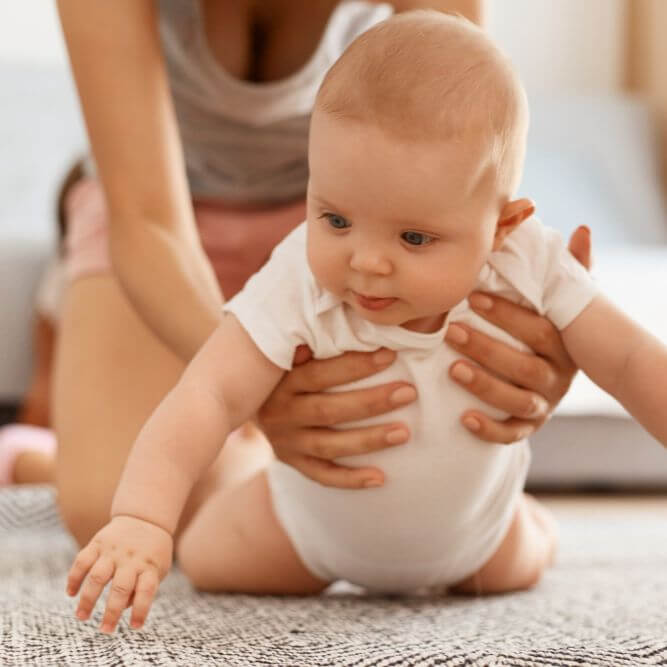 Niemowlę ćwiczy podpór i leżenie na brzuchu pod opieką fizjoterapeuty